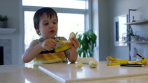 Toddler boy peeling banana 