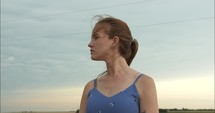 Closeup of a young woman worshipping, contemplating, praying outside in nature in a wheat field.