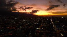 Aerial shot drone hovers over city as sun sets in the distance