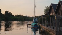 Small sailing boat on a river near wooden cabins and lodges, adventure and outdoors clip