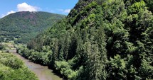View Of Aries River And Forested Apuseni Mountain With Wooden Cross On Top In Transylvania, Romania. aerial drone tilt-up