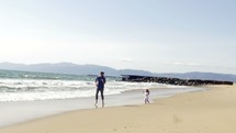 father and daughter running on a beach 
