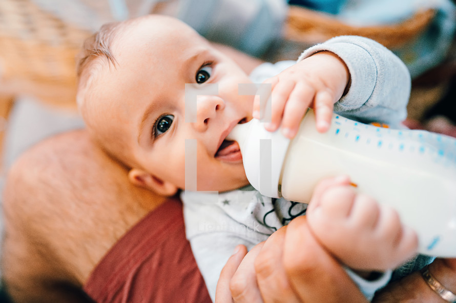 Little baby boy drinking mother milk from the bottle and smiling. High quality photo