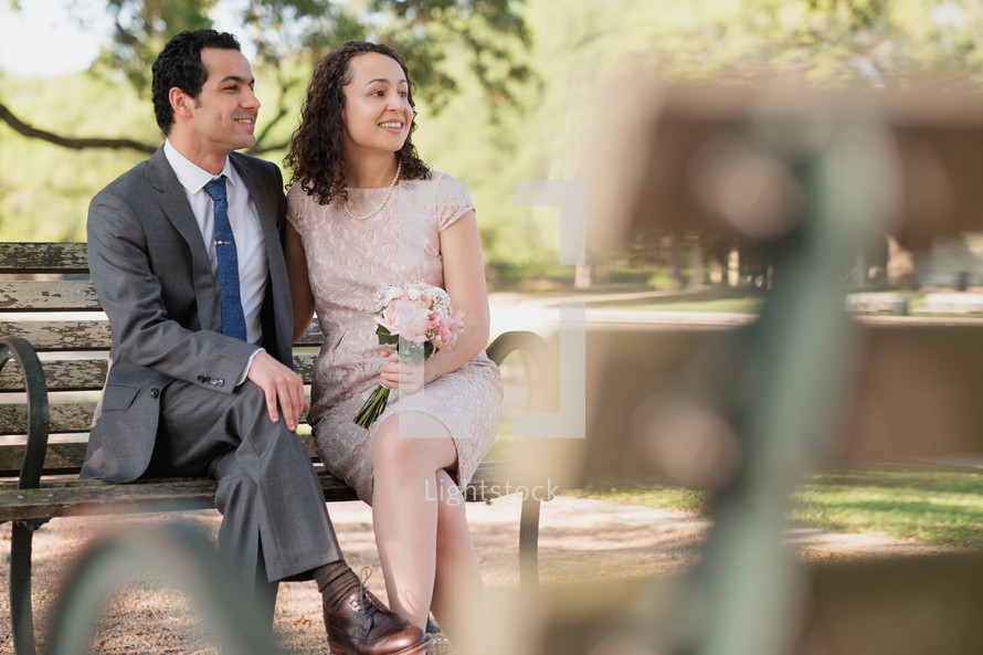 bride and groom sitting on a bench 