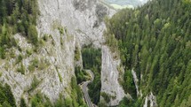 Aerial view of a winding road in a towering canyon of Cheile Bicazului in Romania.