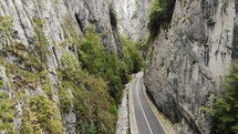Aerial view of cars driving on a narrow road through towering cliffs in Bicaz Gorge in Romania.
