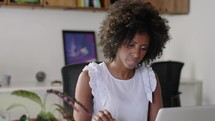 Happy Black Businesswoman Using Computer in Modern Office with Colleagues. Stylish Beautiful Manager Smiling, Working on Financial and Marketing Projects. Drinking Tea or Coffee from a Mug.
