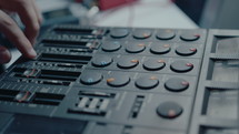 Close-up shot of hand of musician using slider and knobs on vintage multitrack cassette recorder when creating his own music
