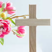 Pink flowers with Easter egg decoration and wooden cross
