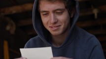 A happy, smiling young man, teenage boy looks at a picture of his dad in cinematic slow motion.