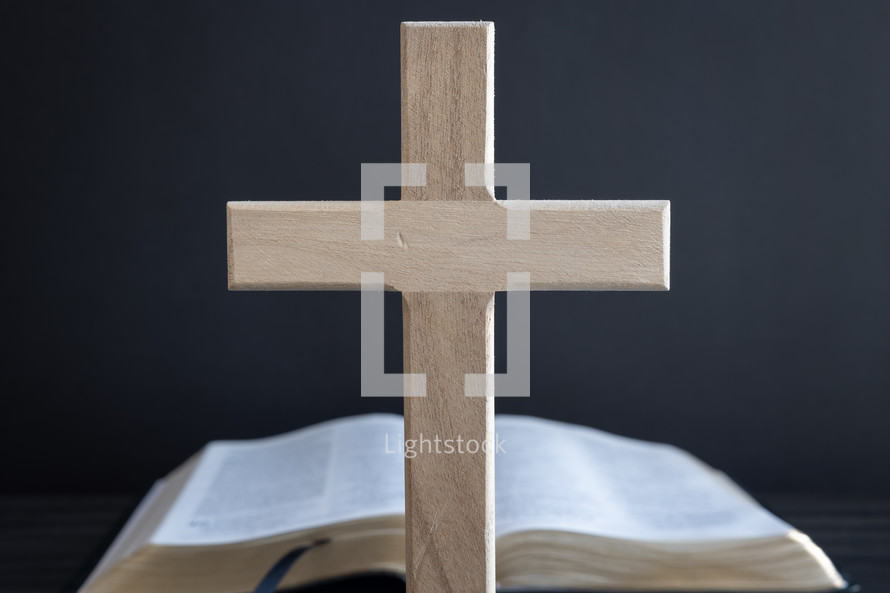 Wood cross standing in front of open bible