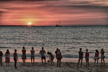 people on a beach at sunset 