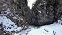 Cliffs And Frozen River In Winter Forest At Daytime - aerial drone shot