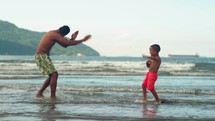 Dad playing and fooling around with his toddler son at the beach having fun. Multi ethnic father playing with his young son at the beach, priceless parenthood moments.
