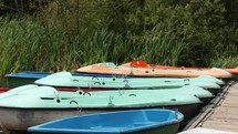 Static shot of small boats docked on a lake.