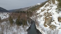 Flying over Winter River in Mountain Valley