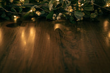fairy lights and branches with white berries on a wood floor 
