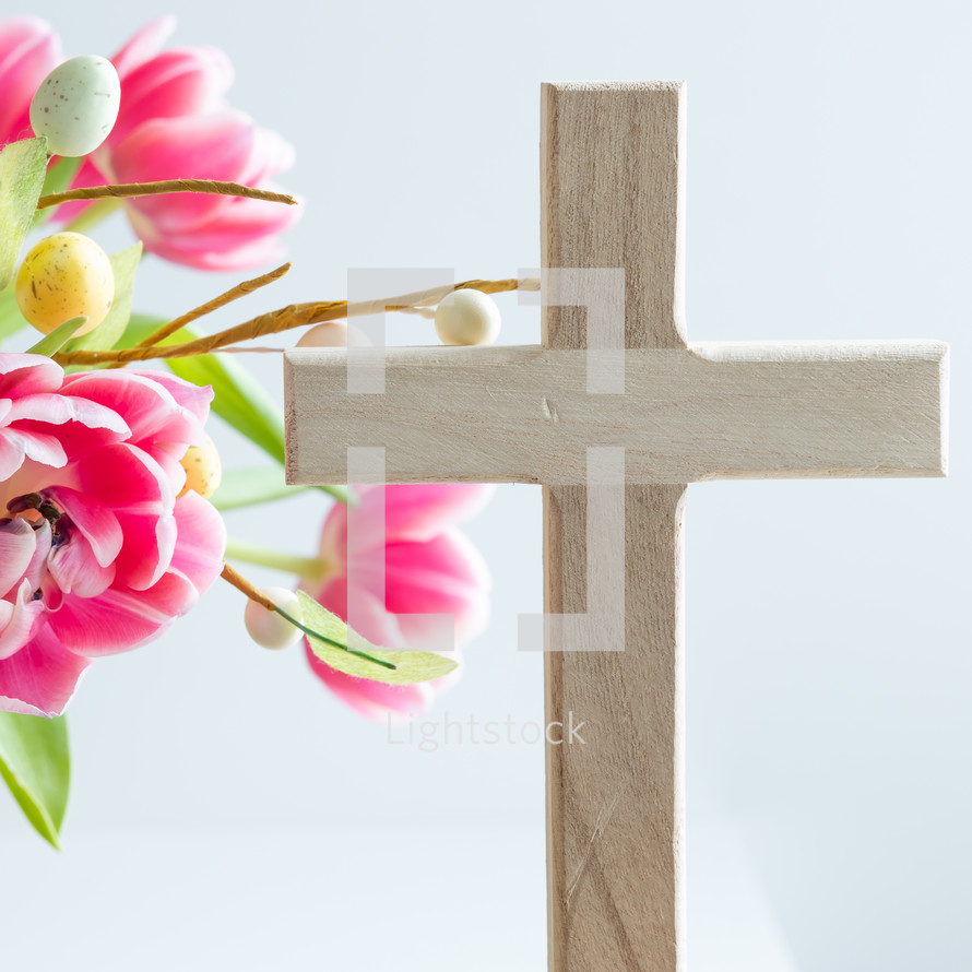 Pink flowers with Easter egg decoration and wooden cross
