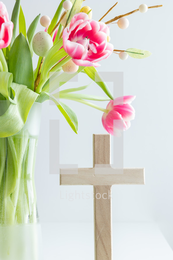 Pink flowers with Easter egg decoration and wooden cross
