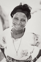 Smiling woman with head scarf and key necklace.