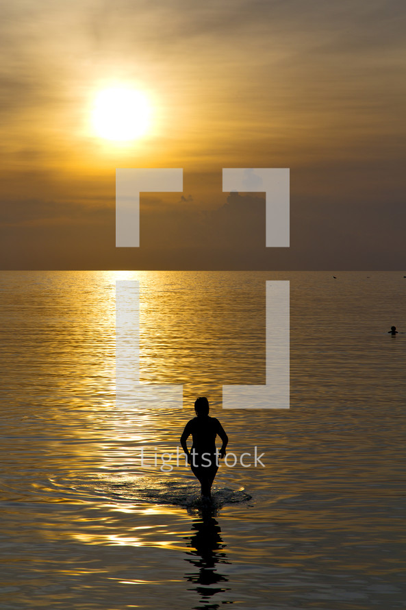 silhouette of a woman in the water of the Kho Phangan Bay at sunset 