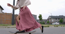 Female South American latina skateboarder pushes off on neighbourhood street - close up on feet