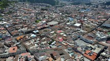 Aerial shot drone flies forward over downtown Quito and slowly pans the camera down as the drone approaches the central market and central bus station