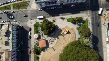 Aerial shot drone flies forward as it pans up from camera facing down over park to looking at the blue sea of the marina