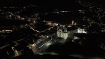 Drone flies over Igreja de Nossa Senhora do Carmo to Praça Tiradentes in Ouro Preto, Brazil at night