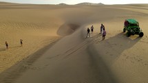Aerial shot drone flies to left as sandboarder wipes out going down dune near desert oasis Huacachina, Peru