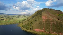Aerial shot drone orbits to left around large hill overlooking Lake Huaypo in the Sacred Valley