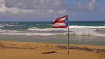 Puerto Rico Flag On The Beach With Ocean Surf Blowing In The Shortline Travel Destination