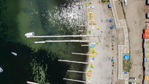 Aerial shot drone flies backwards camera facing down over boat docks with one boat sailing in marina