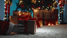 Hand of Santa Claus is deliver the Christmas gift box under the tree 