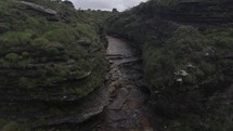 Drone flies backwards from river over Fumaça waterfall in Chapada Diamantina, Brazil