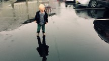 toddler boy splashing in a puddle 