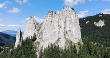 Aerial approach shot Of Jagged And Barren Mountain Of The Lonely Rock  With Evergreen Forest In Romania. 