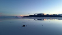 Aerial shot drone orbits 360 degrees around photographers on the salt flats taking pictures of the sunset