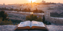 Bible open looking out towards Jerusalem Old City, Israel from the viewpoint of Mount of Olives with Copy space at Sunset