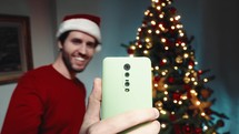 Boy making the video call for Christmas with smartphone against the tree