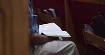 Man reading the Bible in a church pew.