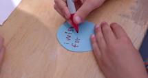 Young boy writing what he wishes for on piece of paper - close up on hands