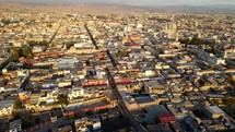 Aerial shot drone flies over Arequipa toward Plaza de Armas at dusk with the sun behind the camera