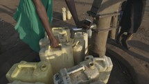 Filling Up Containers With Water From Well In Africa Developing Community