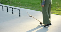 Female skateboarder practices dropping in on flat ground before taking it to a ramp - focus on feet