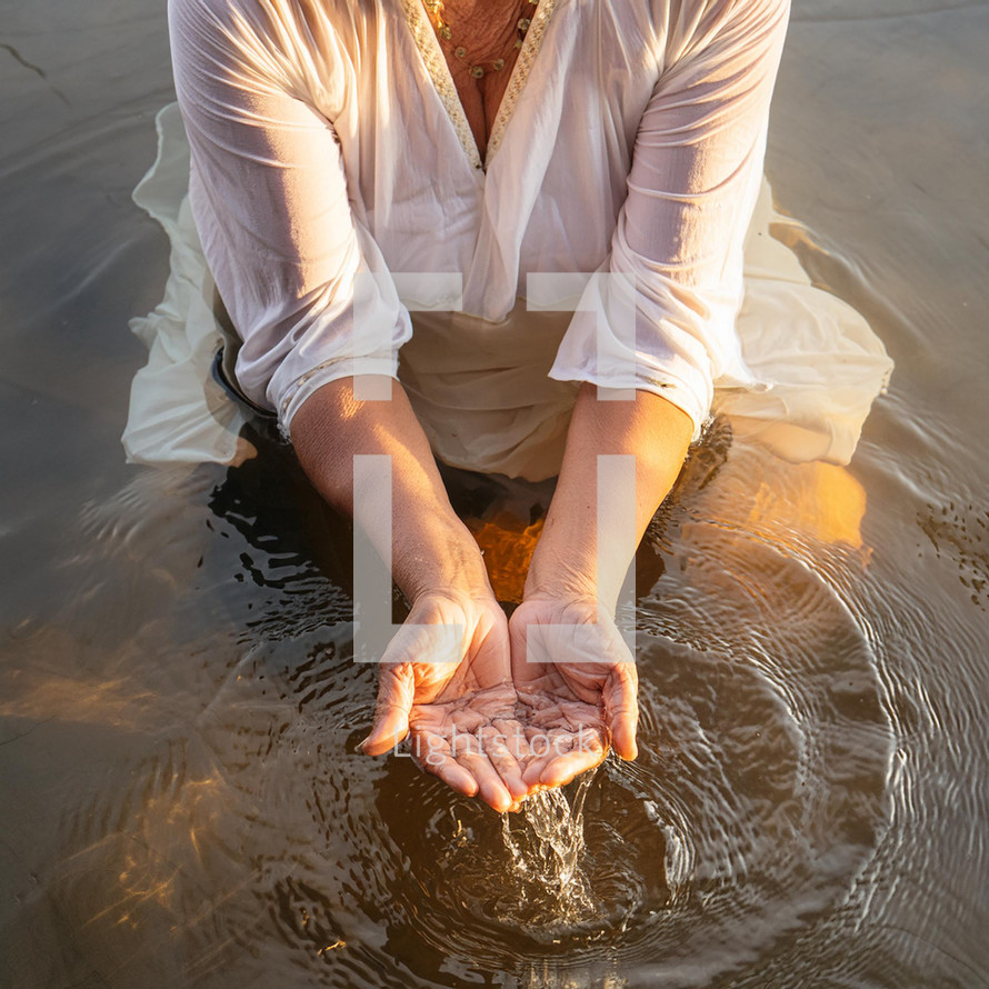 Hands of a woman holding water during a river Christian baptism sacrament.