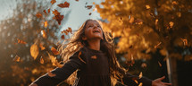 A young girl with long hair playing in the autumn leaves