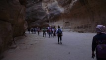 Gimbal of Tourists walking through slot canyon in Petra Jordan Tour Group Wonder of the World Ancient civilization