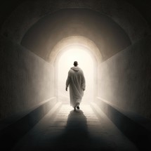 Back view of a person walking towards a bright light at the end of a dark tunnel