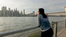 Steady cam shot young female tourist enjoying manhattan view sunset on sunny river bank
